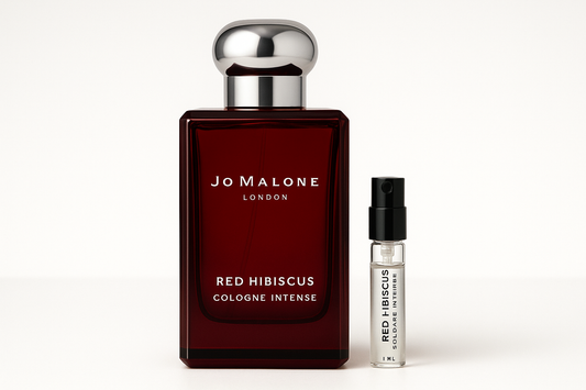 ジョー マローン レッド ハイビスカス コロン インテンスの 1ml サンプルが、濃い赤色のボトルに白い文字が書かれたジョー マローン レッド ハイビスカス コロン インテンスの 100ml 香水ボトルの横に立っています。